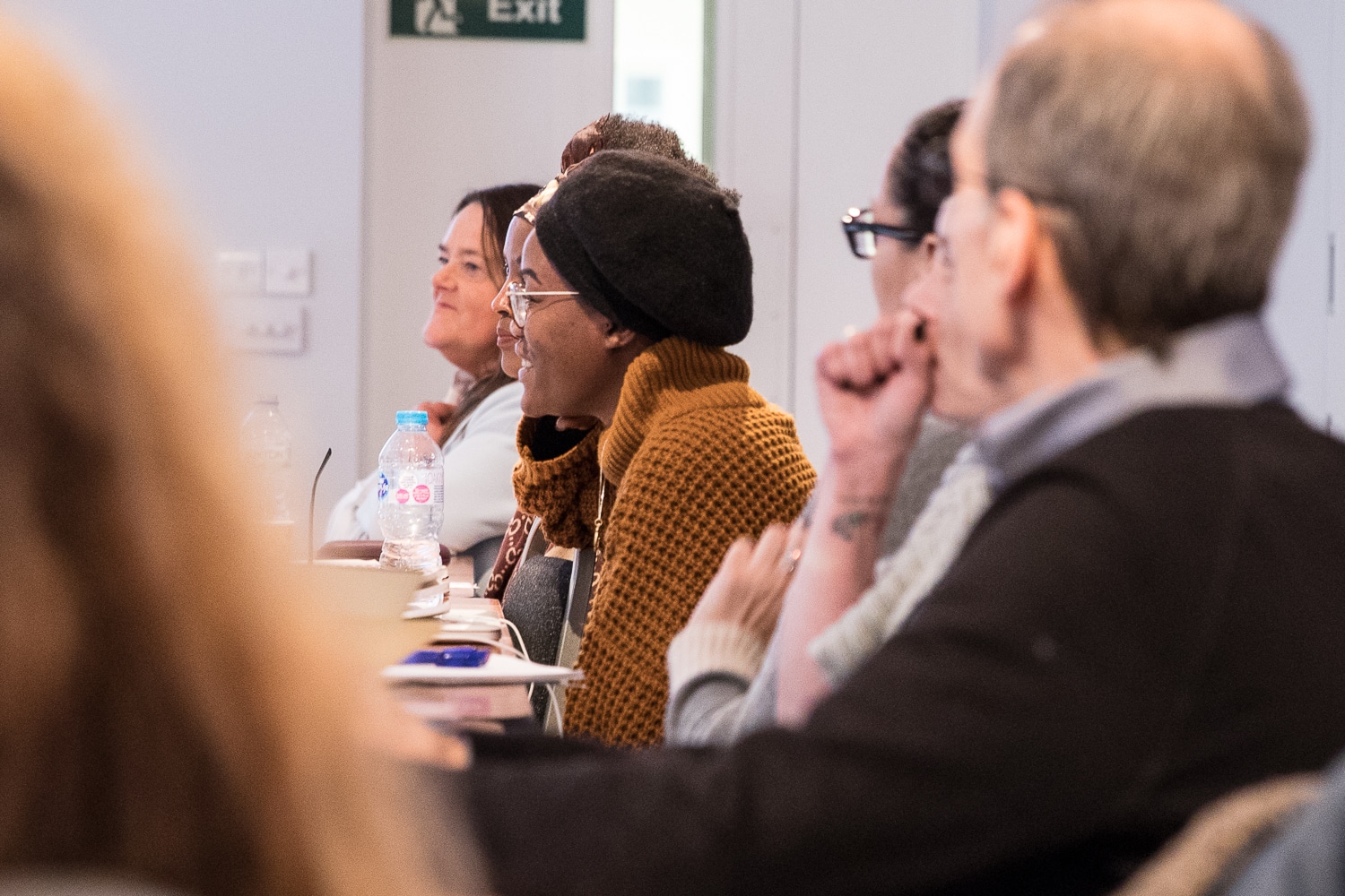 Close up photo of people sat around a conference table listening to a training session.
