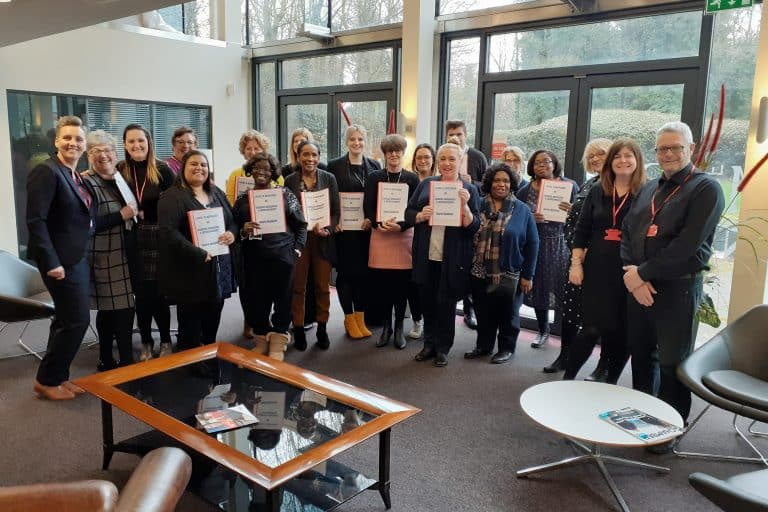 Group of learners holding their certificates next to their tutors