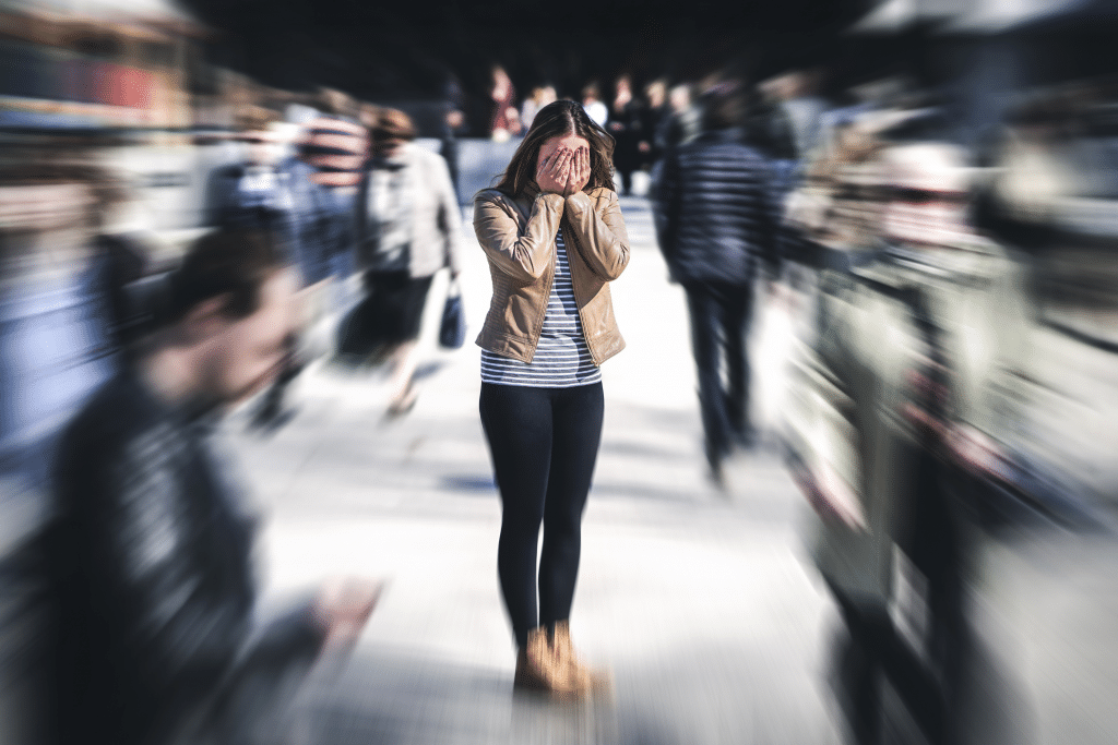 Woman covering her face in a public swuare having a panic attack